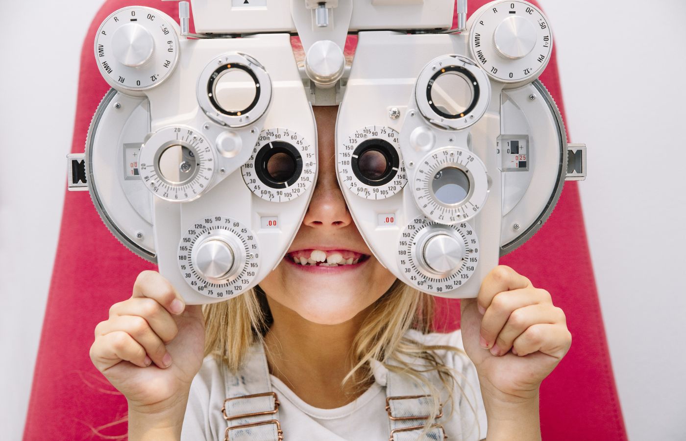 Child during comprehensive eye exam holding phoropter lenses.