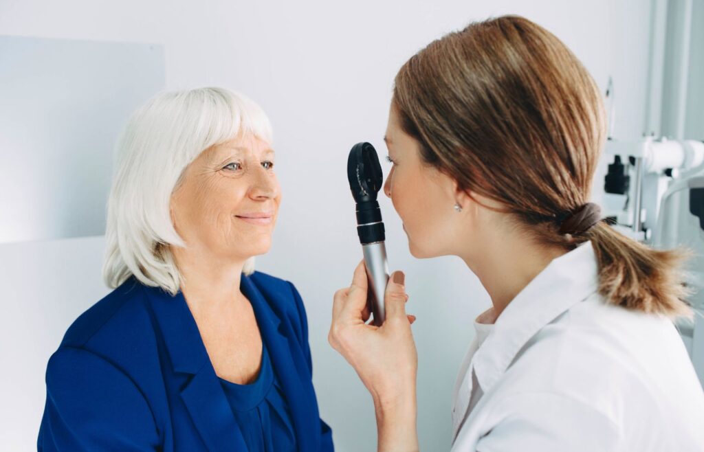 Optician at Mango Optic checking woman's eyes during comprehensive eye exam.