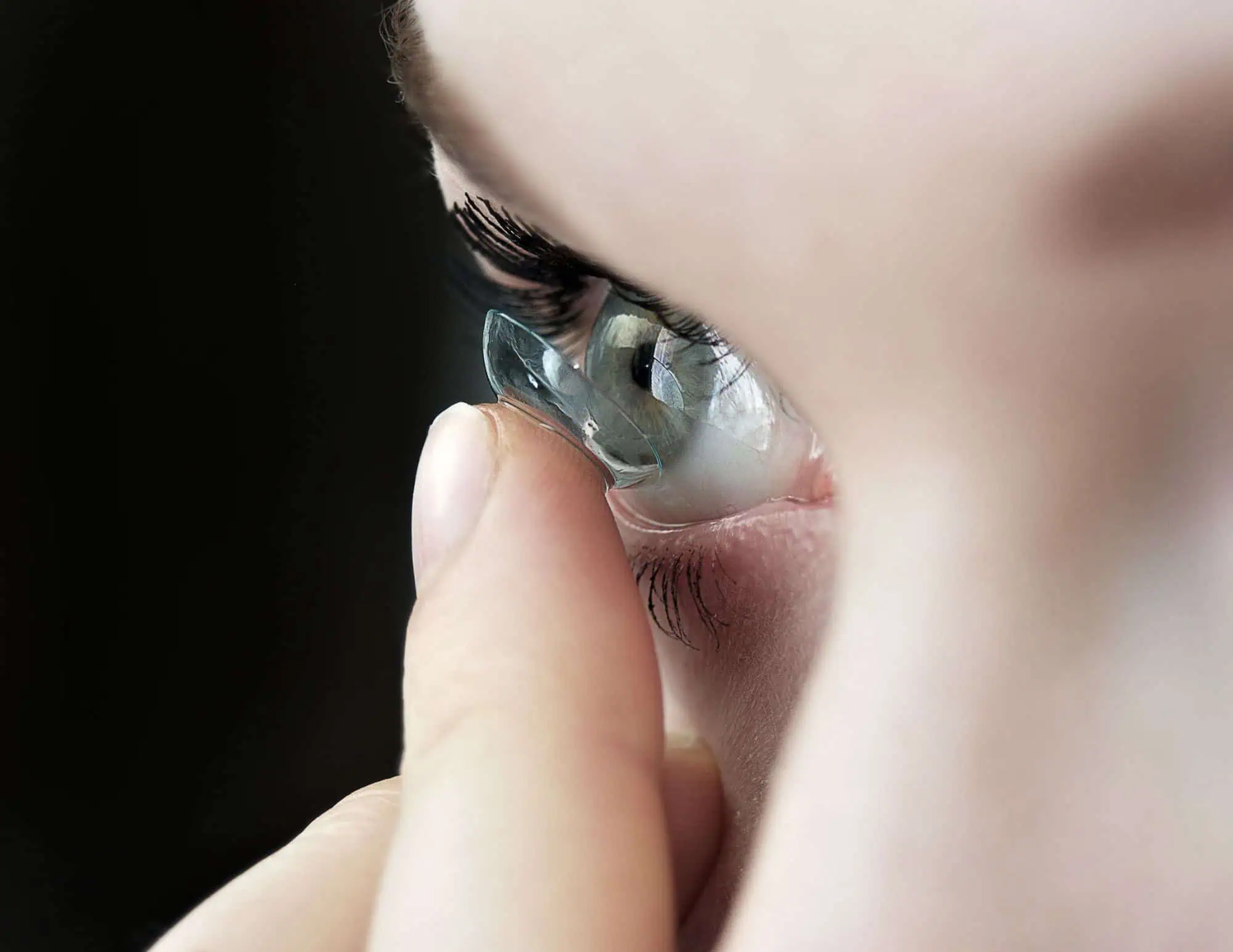 Mujer colocándose una lente de contacto en Mango Optic en Boca Raton.