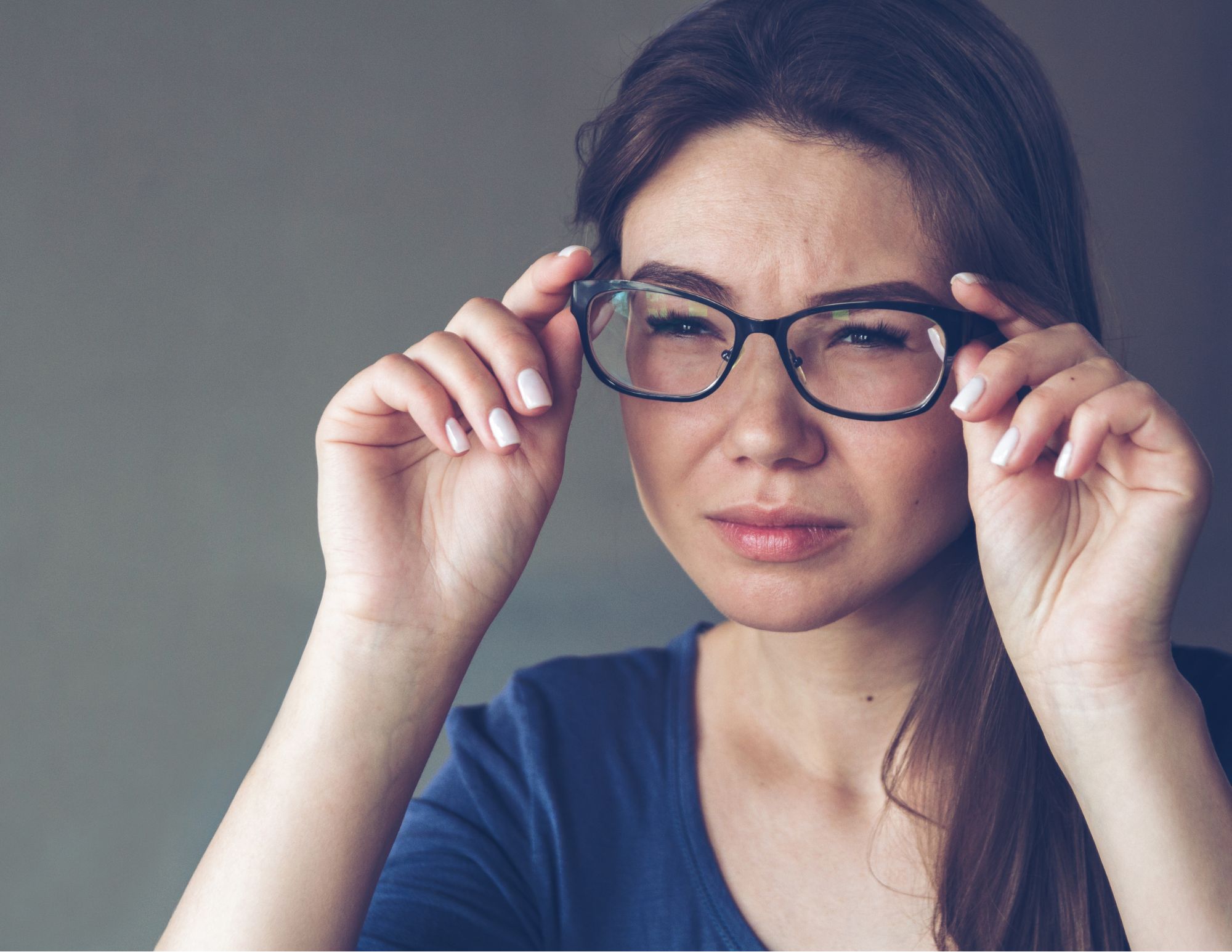 Woman straining her eyes while wearing glasses.