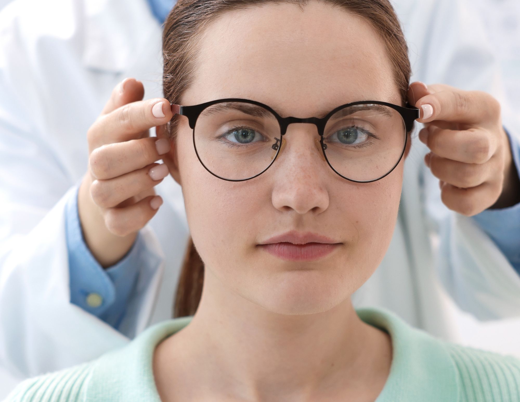 Optician fitting a pair of glasses on a woman.
