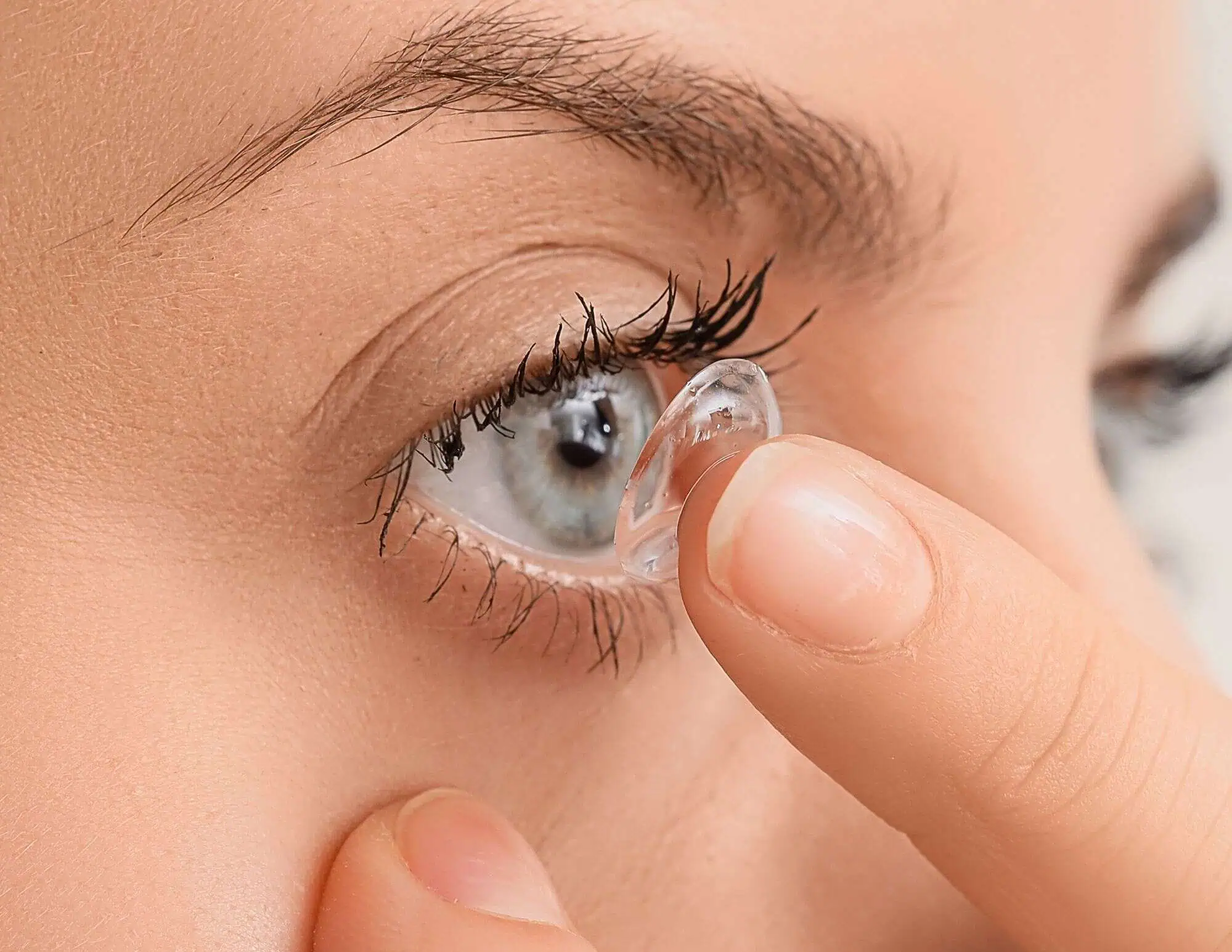 Woman putting on a contact lens from Mango Optic in Boca Raton